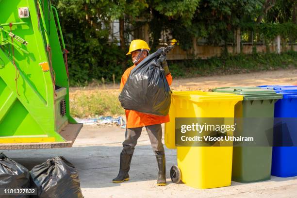 garbage man filling the back of their trucks. - vuilnisman stockfoto's en -beelden