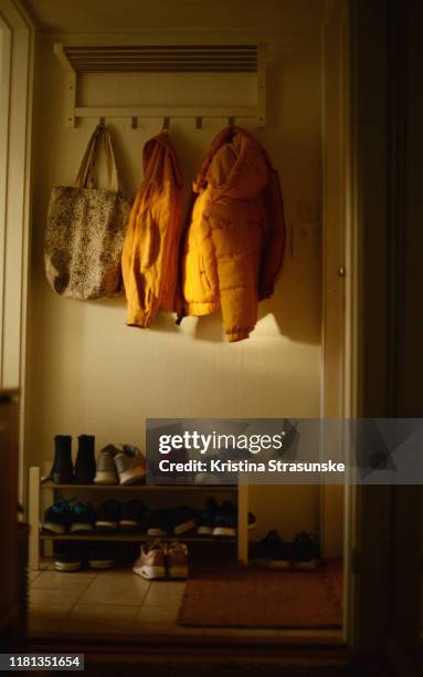 two yellow jackets and a tote bags hanging on a rack over a shoe shelf - shoes closet ストックフォトと画像