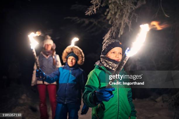 kinderen wandelen in winterbos met fakkels - fakkel stockfoto's en -beelden