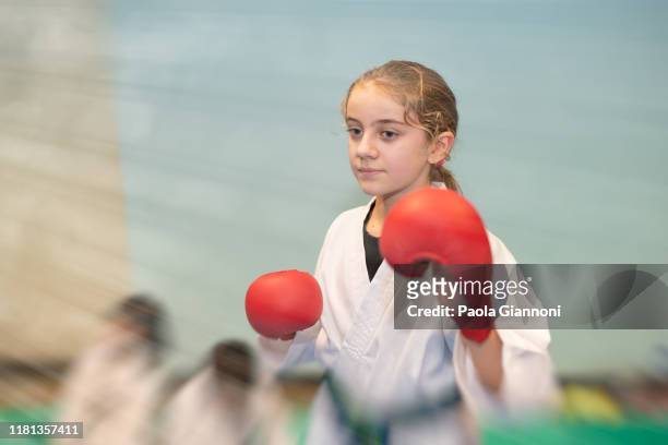 sports and disciplines. martial arts. pre-teen girl concentrated with red boxing gloves during a karate class in gym - kickboxing stock pictures, royalty-free photos & images