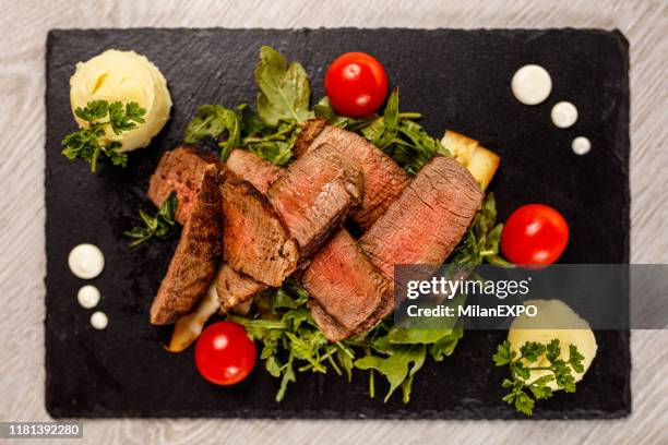 köstliches tagliata steak auf schwarzem steinbrett - viereckiger teller stock-fotos und bilder