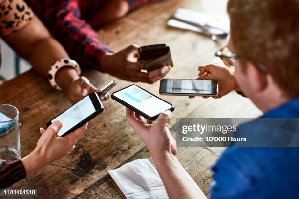 millennials sharing contacts via bluetooth on smartphones - bluetooth photos et images de collection