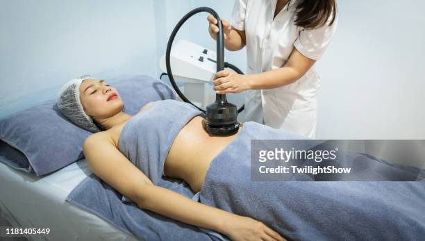 woman doing service with new technology of hardware cosmetology, young woman getting fat removing - fat massage stock pictures, royalty-free photos & images