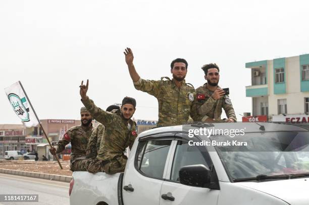 Members of Turkish-backed Free Syrian Army wave on top of a vehicle as they drive back to their base camp on October 16, 2019 in Akcakale, Turkey....