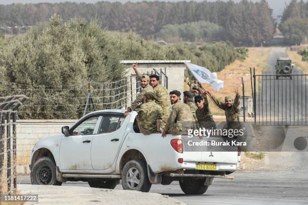 Members of Turkish-backed Free Syrian Army wave on top of a vehicle as they drive back to their base camp on October 16, 2019 in Akcakale, Turkey....
