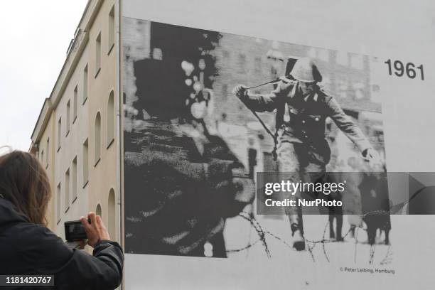 Lady takes a picture of an iconic image of Hans Konrad Schumann, an East German border guard who defected to West Germany during the construction of...