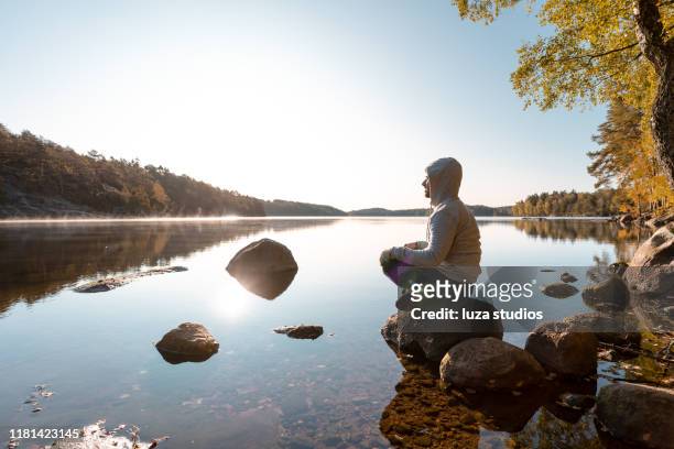 man mediterar vid sjön efter en utomhus övning - meditation outdoors bildbanksfoton och bilder