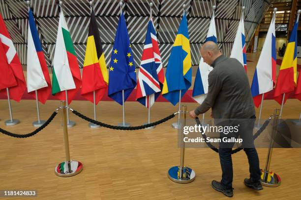 Worker installs a barrier next to the flags of the European Union, the United Kingdom and other EU nations one day prior to a summit of European...