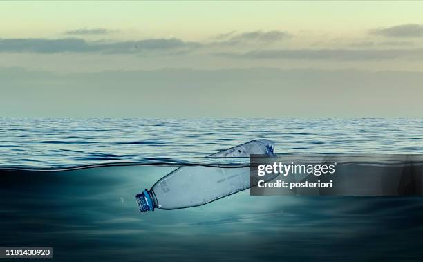 plastikflasche, verschmutzung, die im ozean schwimmt - plastikmaterial stock-fotos und bilder