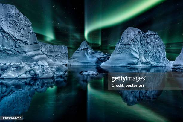 eisberg schwimmt nachts im grünlandfjord mit grüner nordbeleuchtung - grönland stock-fotos und bilder