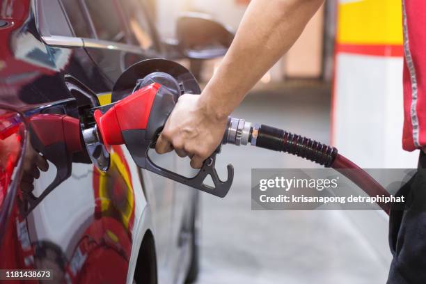 gas station,pumping gasoline fuel in car at gas station.the hand holds the refueling gun - gas station imagens e fotografias de stock