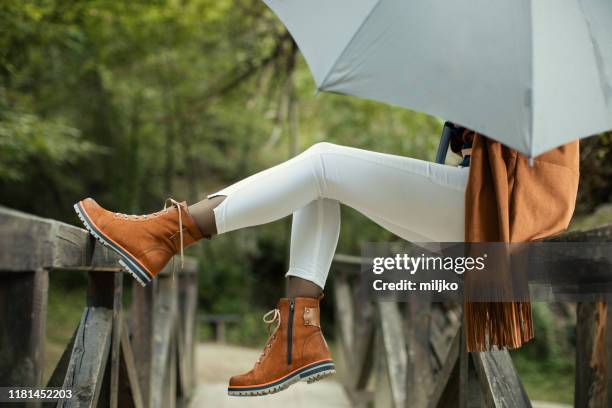 donna con ombrello in piedi sul ponte - boot foto e immagini stock