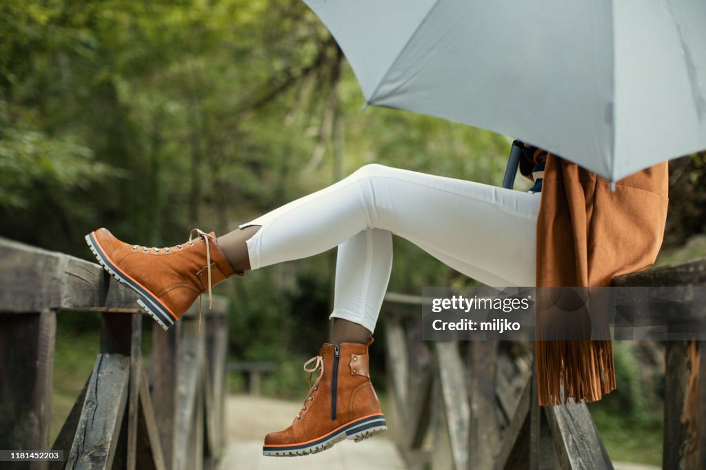 Woman with umbrella standing on bridge