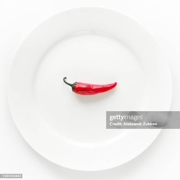 red hot chili pepper on white plate on white background. - peperone rosso foto e immagini stock