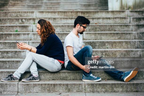 couple after conflict texting on smartphones - cross bores stock pictures, royalty-free photos & images