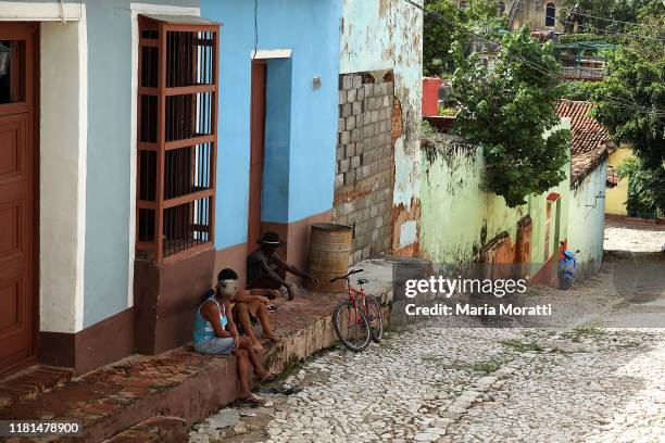 People chat on a cobblestone street of Trinidad on October 8, 2019 in Trinidad, Cuba. Trinidad is a town in the province of Sancti Spíritus, central...