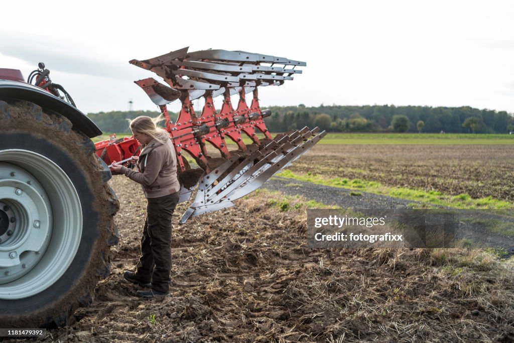 Female farmer repairs a plow in a agricultural field