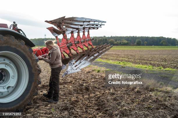 female farmer repairs a plow in a agricultural field - agricultural equipment stock pictures, royalty-free photos & images