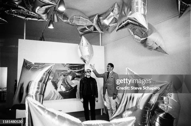 View of American Pop artist Andy Warhol and art dealer Irving Blum stand amidst the formers 'Silver Clouds' installation at the latter's Ferus...