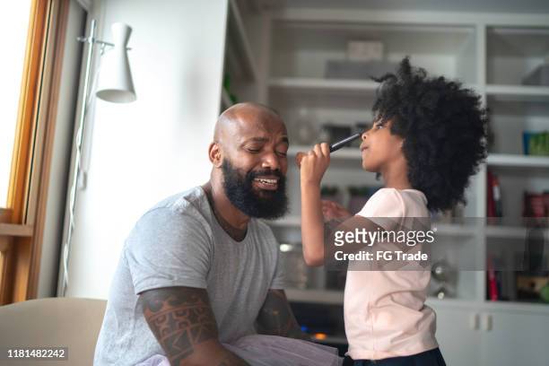 Daughter doing makeup to shy father at home