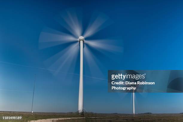 long exposure of two wind turbines along highway 20 in northern nebraska - turning fotografías e imágenes de stock
