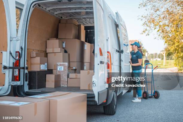 mixed race female worker taking packages from the delivery van - delivery truck stock pictures, royalty-free photos & images