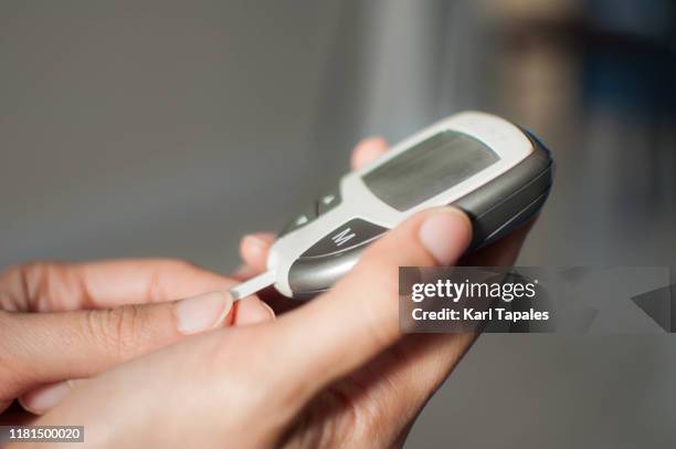 a young woman is using a glucometer - blood glucose stock pictures, royalty-free photos & images