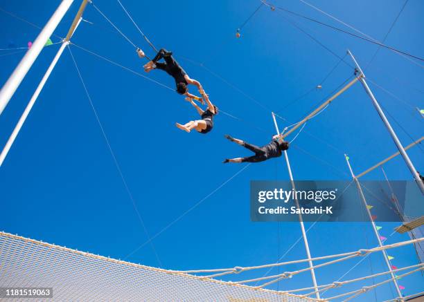 drie trapeze artiesten die de show in de lucht uitvoeren - trapezeartiest stockfoto's en -beelden
