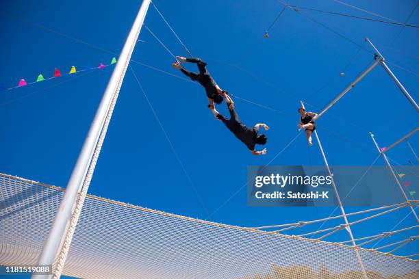 tres trapecistas jugando juntos en el cielo azul - trapecista fotografías e imágenes de stock