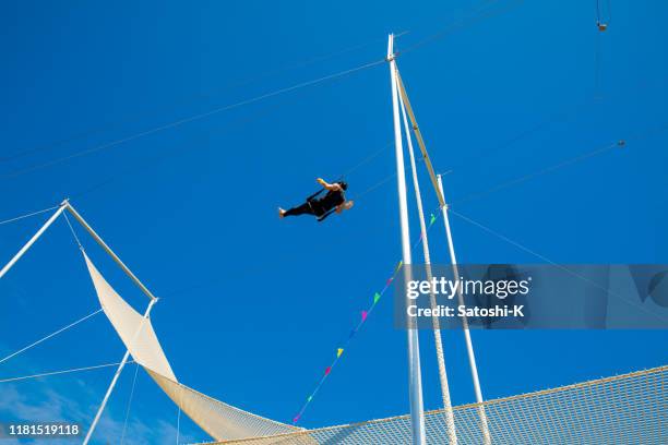 trapeze artist swinging in the blue sky - wide net stock pictures, royalty-free photos & images