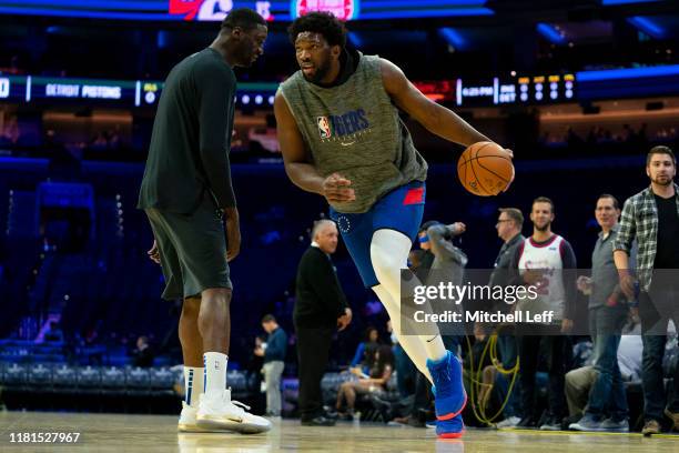 Joel Embiid of the Philadelphia 76ers dribbles around player development coach Roy Hibbert prior the preseason game against the Detroit Pistons at...