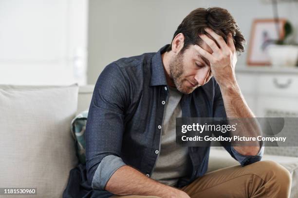 hombre sentado solo en casa mirando triste y angustiado - manos a la cabeza fotografías e imágenes de stock