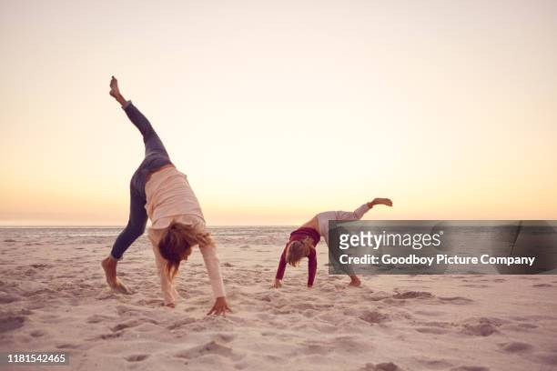 mother and daughter doing cartwheels together at the beach - handstand stock pictures, royalty-free photos & images