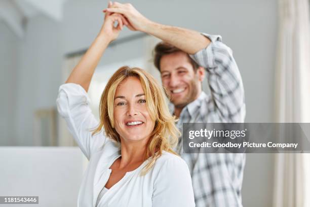 lachend koppel houdt handen en dansen samen thuis - ouder-volwassenen-koppel stockfoto's en -beelden