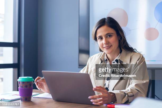 retrato de mujer trabajando en un ordenador portátil en la sala de juntas - mature latin women fotografías e imágenes de stock