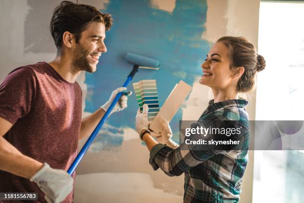 feliz pareja comunicándose mientras elige el color adecuado para su pared. - pared casa fotografías e imágenes de stock