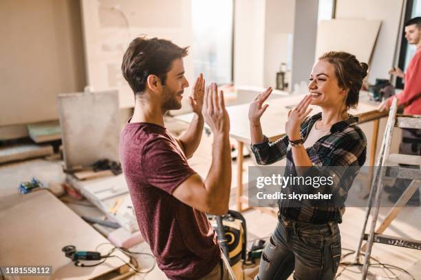couples heureux se donnant l'un l'autre haut-cinq à leur appartement de rénovation. - housework photos et images de collection