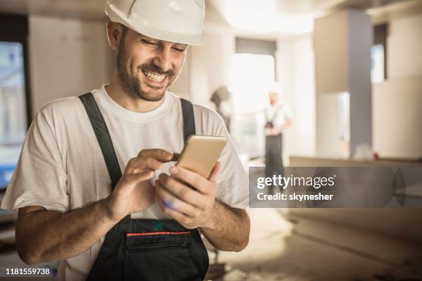 glücklicher bauarbeiter mit handy bei hausseitigem umbau. - construction workers stock-fotos und bilder