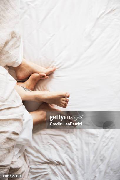 schöne frauen paar zu hause - feet in bed stock-fotos und bilder