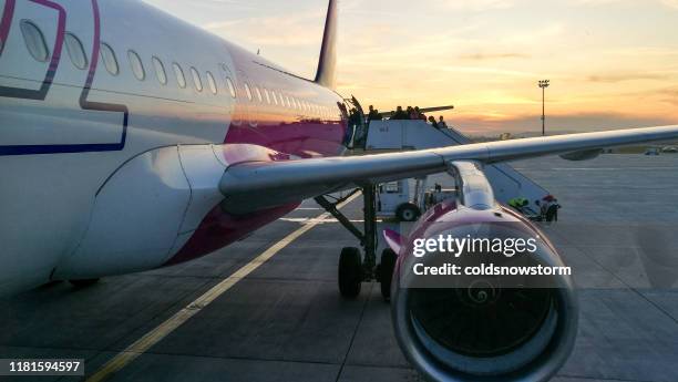 passagiere besteigen wizz air flugzeug im freien bei sonnenuntergang - cluj napoca stock-fotos und bilder