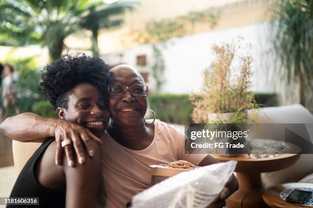 kleindochter geven een verrassing cadeau aan oma - lifestyle moments stockfoto's en -beelden