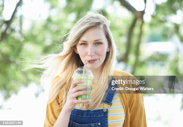 young woman drinking fresh smoothie from plastic free compostable cup. - woman drinking juice stock pictures, royalty-free photos & images