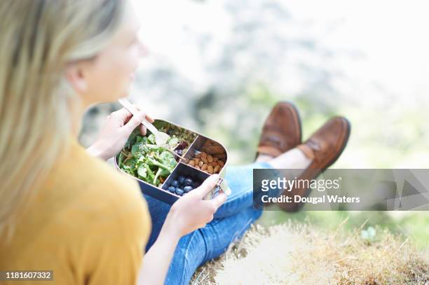 woman sitting in countryside eating healthy plastic free lunch. - lunch lady foto e immagini stock