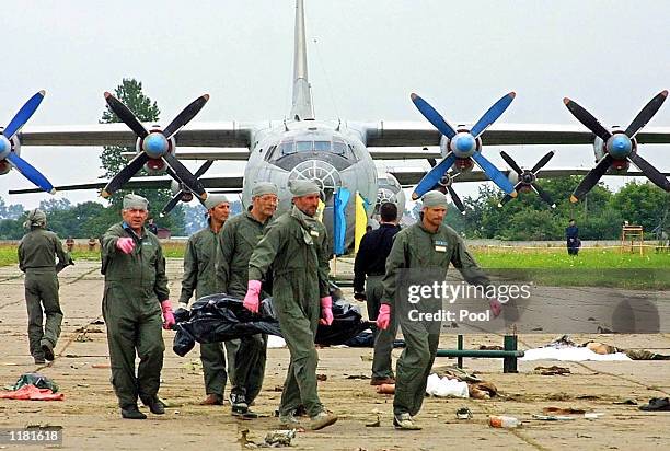 Ukrainian air force officers carry a body of a victim killed when Su-27 fighter plane crashed into a huge crowd of spectators at an air show in the...