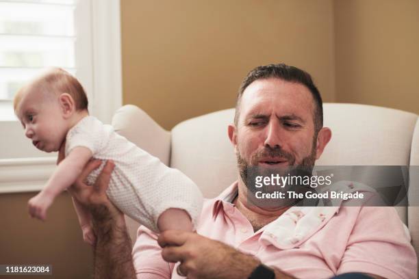 father holding baby with dirty diaper - olor desagradable fotografías e imágenes de stock