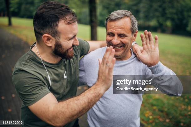 man en zoon trainen in park samen - high five stockfoto's en -beelden