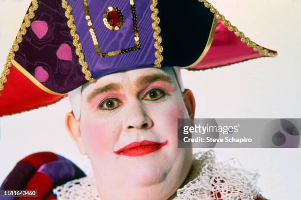 Close-up of Canadian actor and comedian John Candy , in white face paint and a colorful bicorn hat, as he poses against a white background for an...