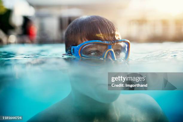 kleine jongen genieten van zwemmen in zwembad - half underwater stockfoto's en -beelden