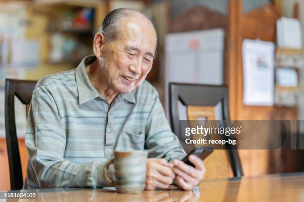ritratto di uomo anziano mentre si utilizza lo smartphone - japanese old man foto e immagini stock
