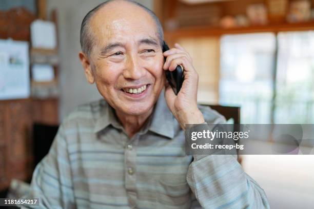 portrait of senior man while talking on smart phone happily - white hair asian man stock pictures, royalty-free photos & images